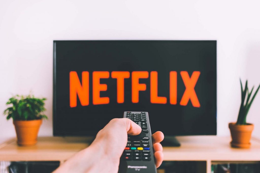 a tv remote pointing at a netflix screen